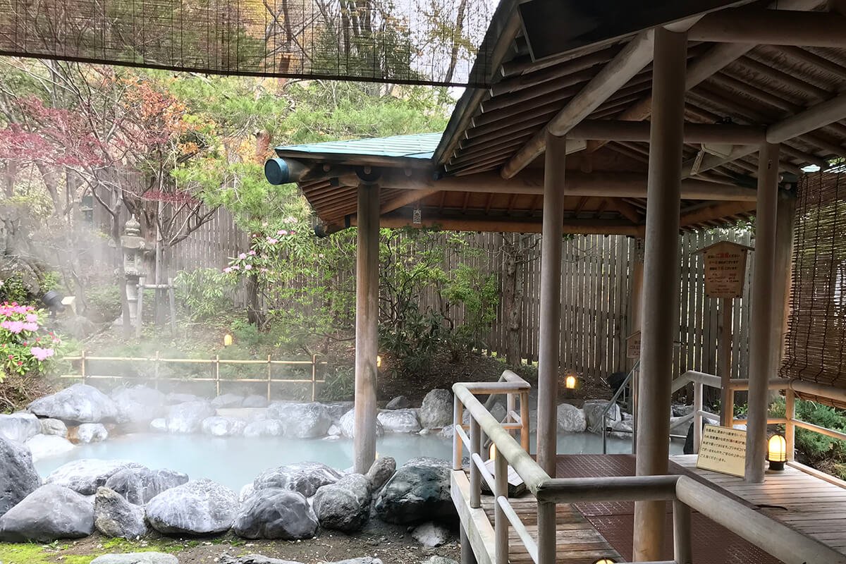 Khu vườn và suối nước nóng onsen ngoài trời yên bình với khung cảnh thiên nhiên vào mùa thu.