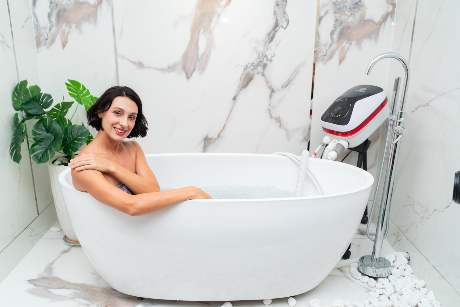 Onsena SPA - Máy Tắm Thủy Liệu Khoáng Nóng Onsen Nhật Bản 103 Người phụ nữ thư giãn trong bồn tắm sang trọng với cây xanh, nền vân đá và máy massage nước.