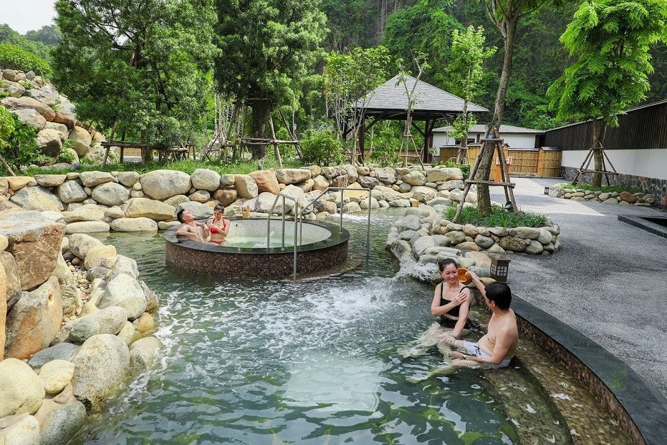 Khu nghỉ dưỡng suối nước nóng thiên nhiên xanh mát, khách thư giãn trong hồ bơi ngoài trời.