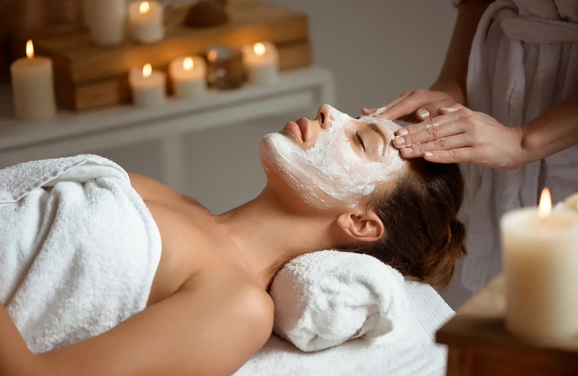 Người phụ nữ thư giãn trong spa với mặt nạ dưỡng da, ánh nến dịu nhẹ, mang lại cảm giác thoải mái và thư giãn.