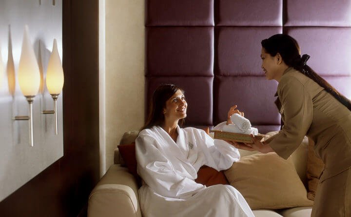 Người phụ nữ trong spa nhận khăn từ nhân viên, tạo không gian thư giãn và thoải mái.