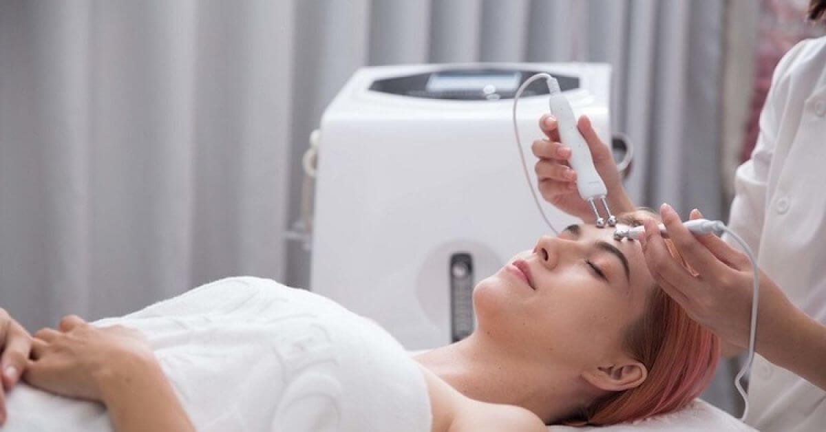 Người phụ nữ đang nhận liệu trình chăm sóc da mặt với thiết bị thẩm mỹ tại spa, thư giãn và cải thiện làn da.