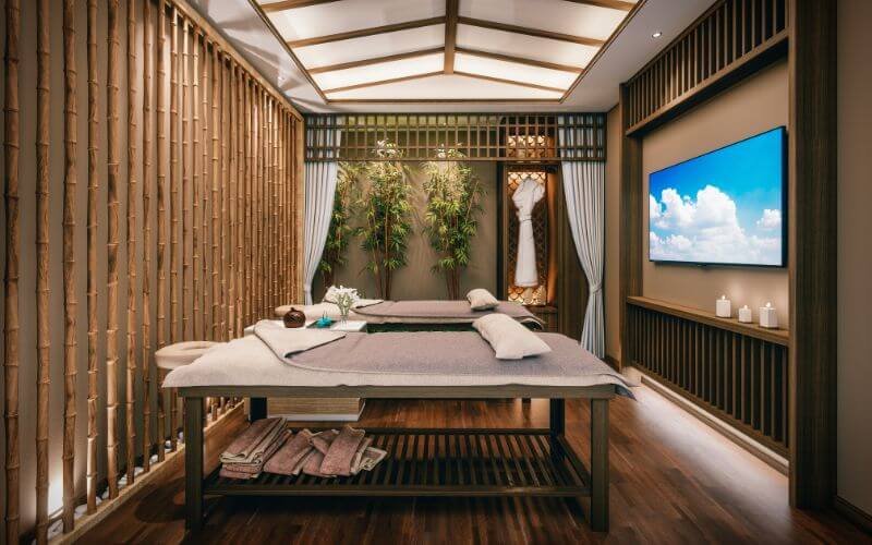 Phòng spa sang trọng với giường massage đôi, trang trí tre và màn hình lớn hiển thị bầu trời xanh.