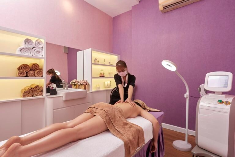 Nhân viên đang mát-xa cho khách hàng trong phòng trị liệu sang trọng với tường màu tím.