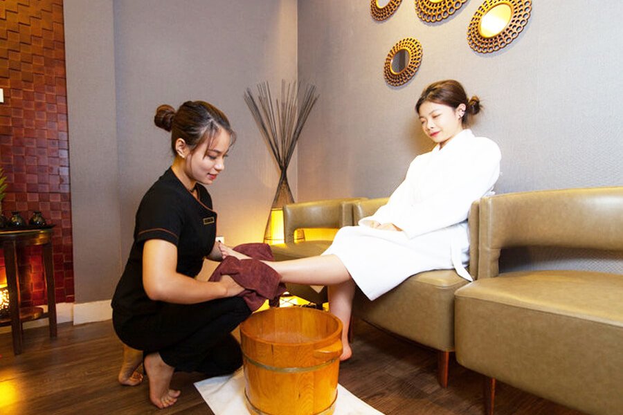Nhân viên spa chăm sóc chân khách hàng trong không gian thư giãn, sang trọng.