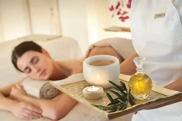 Người phụ nữ thư giãn tại spa với nến và dầu massage, tạo không gian thư giãn tối đa.
