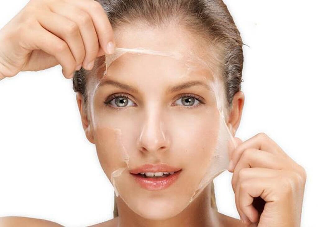 Người phụ nữ đang bóc mặt nạ dưỡng da, phần mặt nạ trong suốt giúp làm sạch và dưỡng ẩm da mặt.