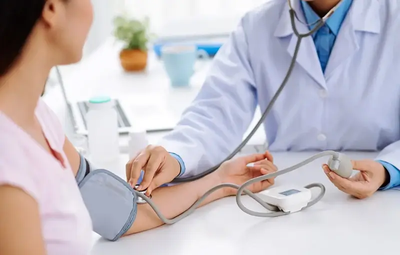 Bác sĩ đo huyết áp cho bệnh nhân nữ trong phòng khám hiện đại.
