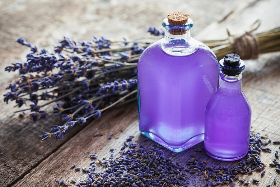 Chai tinh dầu oải hương trên bàn gỗ với hoa oải hương khô, làm dịu căng thẳng và thư giãn.