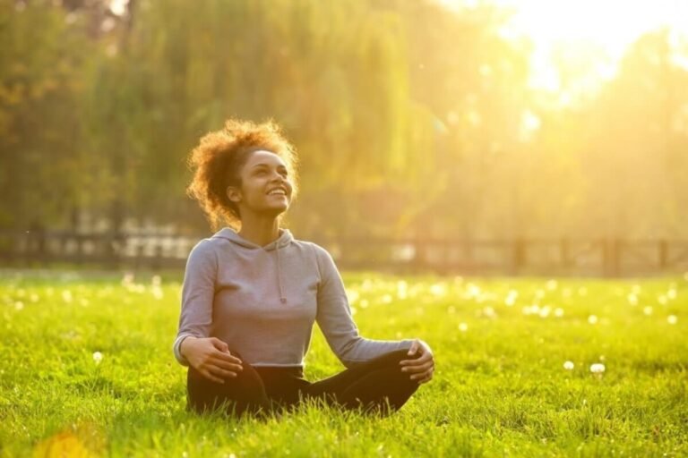 Người phụ nữ thư giãn thiền ngoài trời, ánh sáng mặt trời chiếu sáng trong công viên xanh tươi.