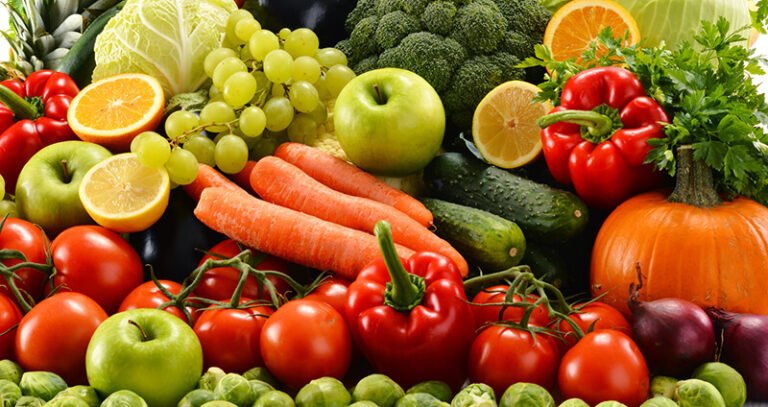 Rau củ quả tươi ngon bao gồm cà chua, ớt, cà rốt, bí đỏ, và táo xanh, bày trí gọn gàng trên bàn.