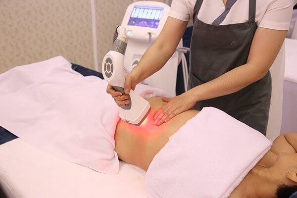Nhân viên spa thực hiện liệu pháp giảm béo bằng máy, giúp da mịn màng và săn chắc hơn.