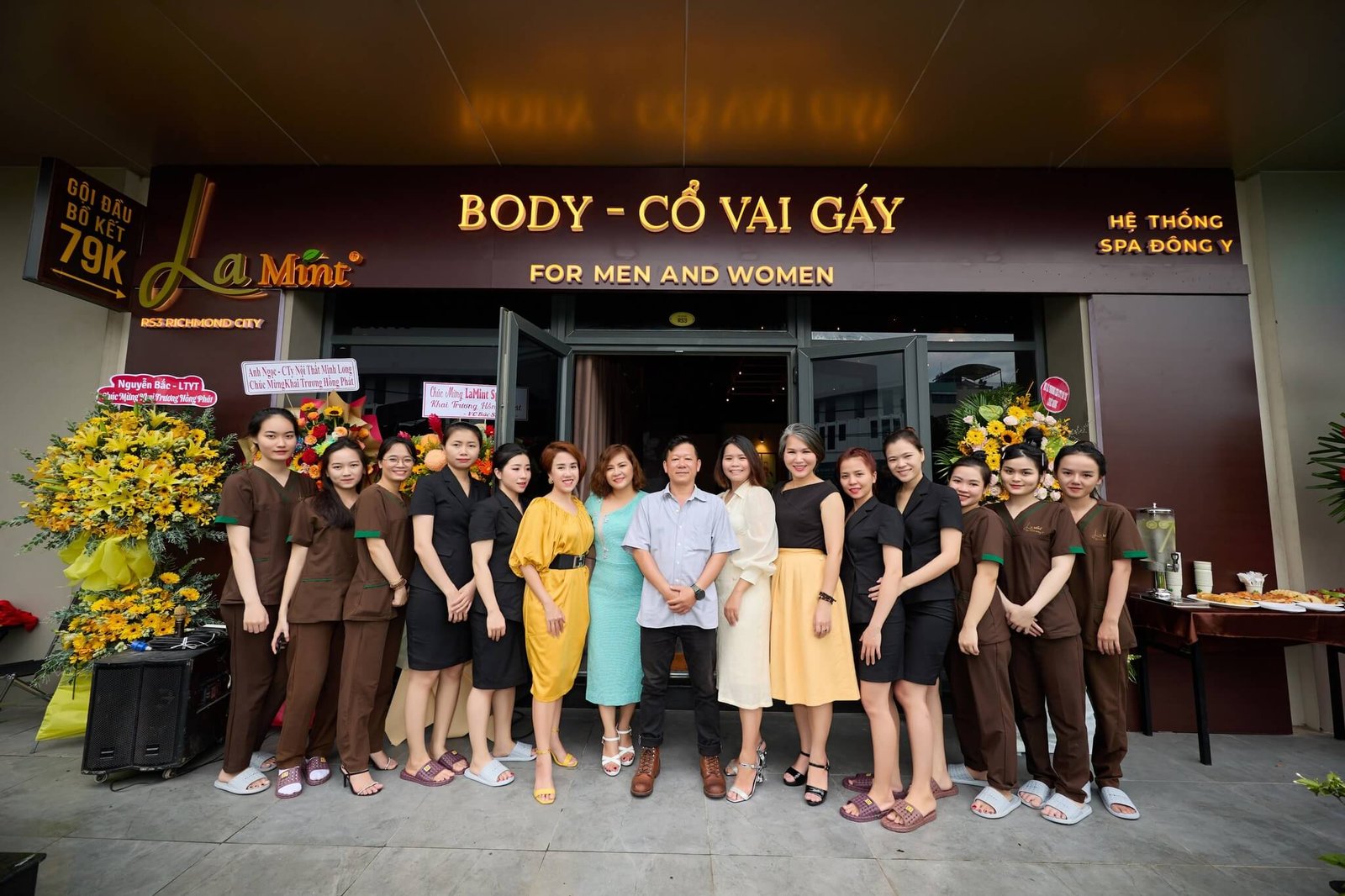 Nhân viên spa La Mint đứng trước cửa hàng với bó hoa chúc mừng khai trương.