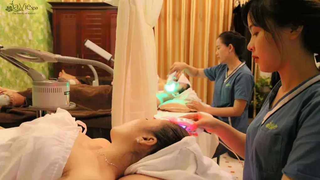 Nhân viên spa thực hiện liệu trình chăm sóc da mặt cho khách hàng, sử dụng thiết bị hiện đại trong không gian thư giãn.