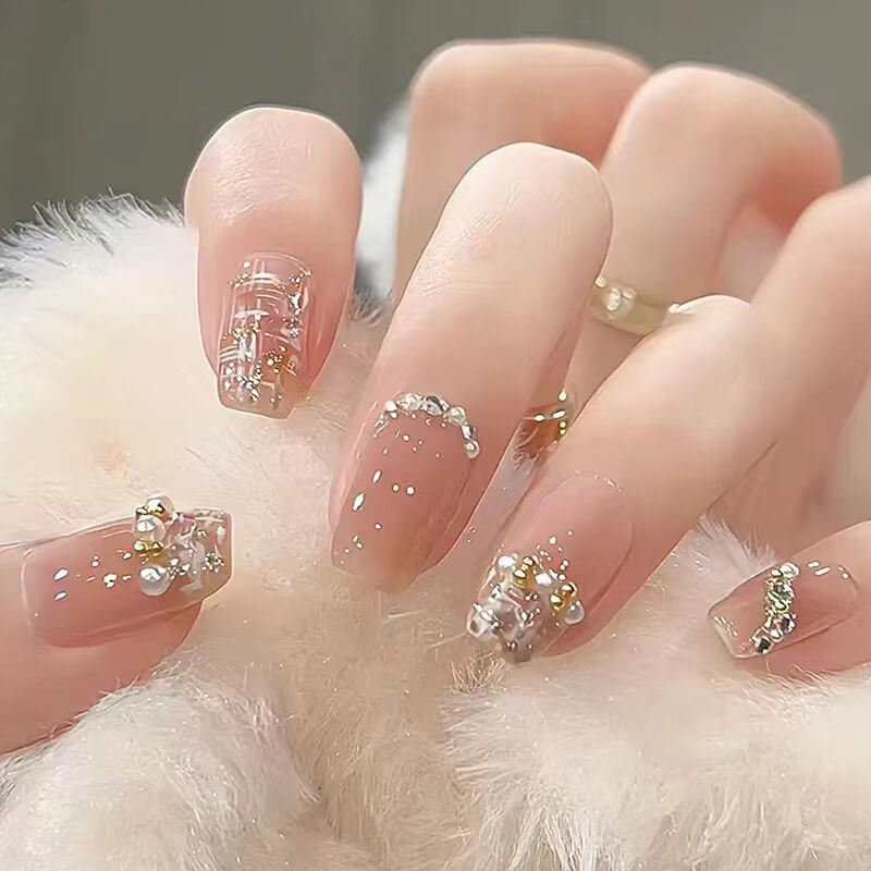 Bộ móng tay đính đá và kim tuyến lấp lánh, thiết kế đẹp mắt trên nền màu nude tinh tế.