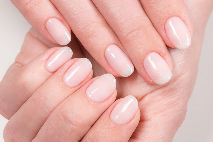 Bàn tay với móng tay sơn màu hồng nhạt, sáng bóng, thể hiện sự chăm sóc và làm đẹp móng tay chuyên nghiệp.