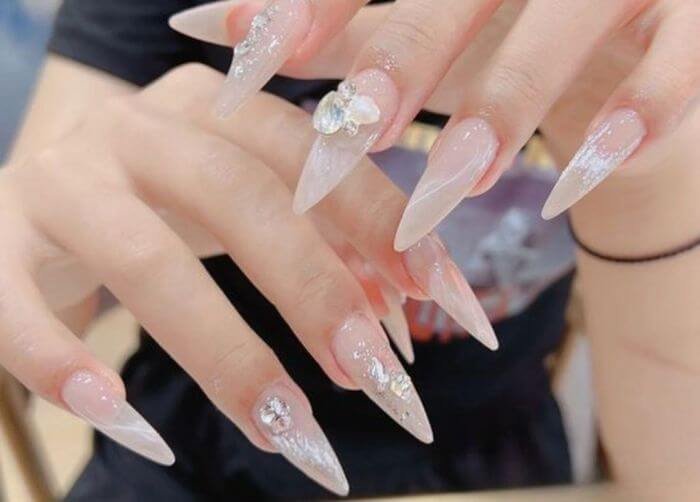 Móng tay dài nhọn đính đá lấp lánh, phong cách nghệ thuật nail sang trọng và sáng tạo.