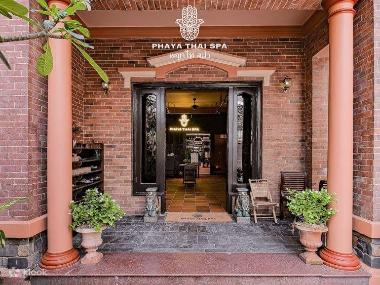 Lối vào sang trọng của Phaya Thai Spa với cửa gỗ và cây xanh trang trí.
