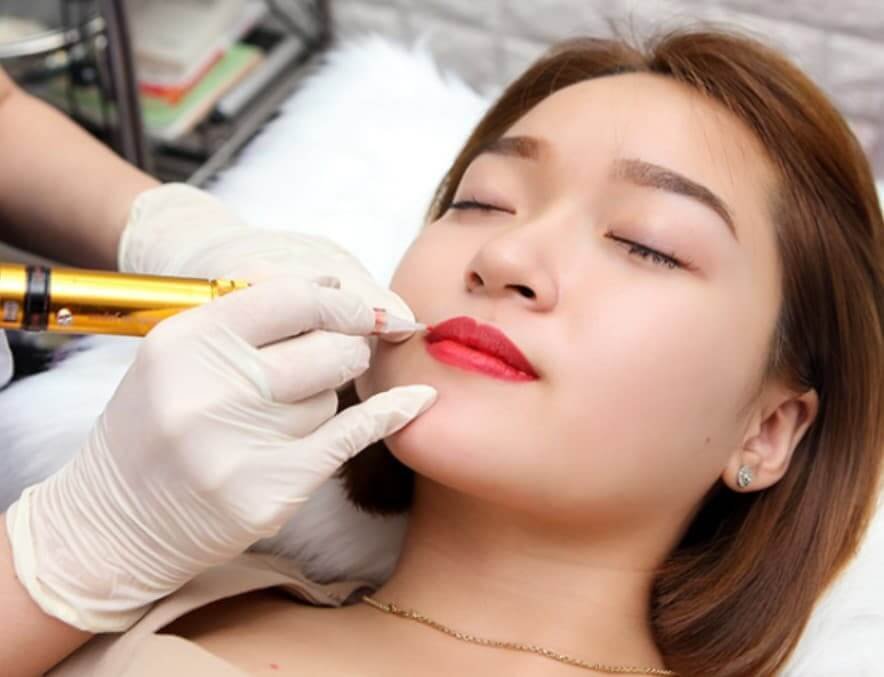 Đang xăm môi tại spa, cô gái trẻ nằm thư giãn trong liệu trình làm đẹp chuyên nghiệp.