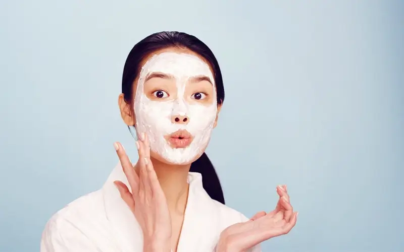 Người phụ nữ đắp mặt nạ dưỡng da, cảm giác thư giãn, phông nền xanh, chăm sóc sức khỏe và sắc đẹp.