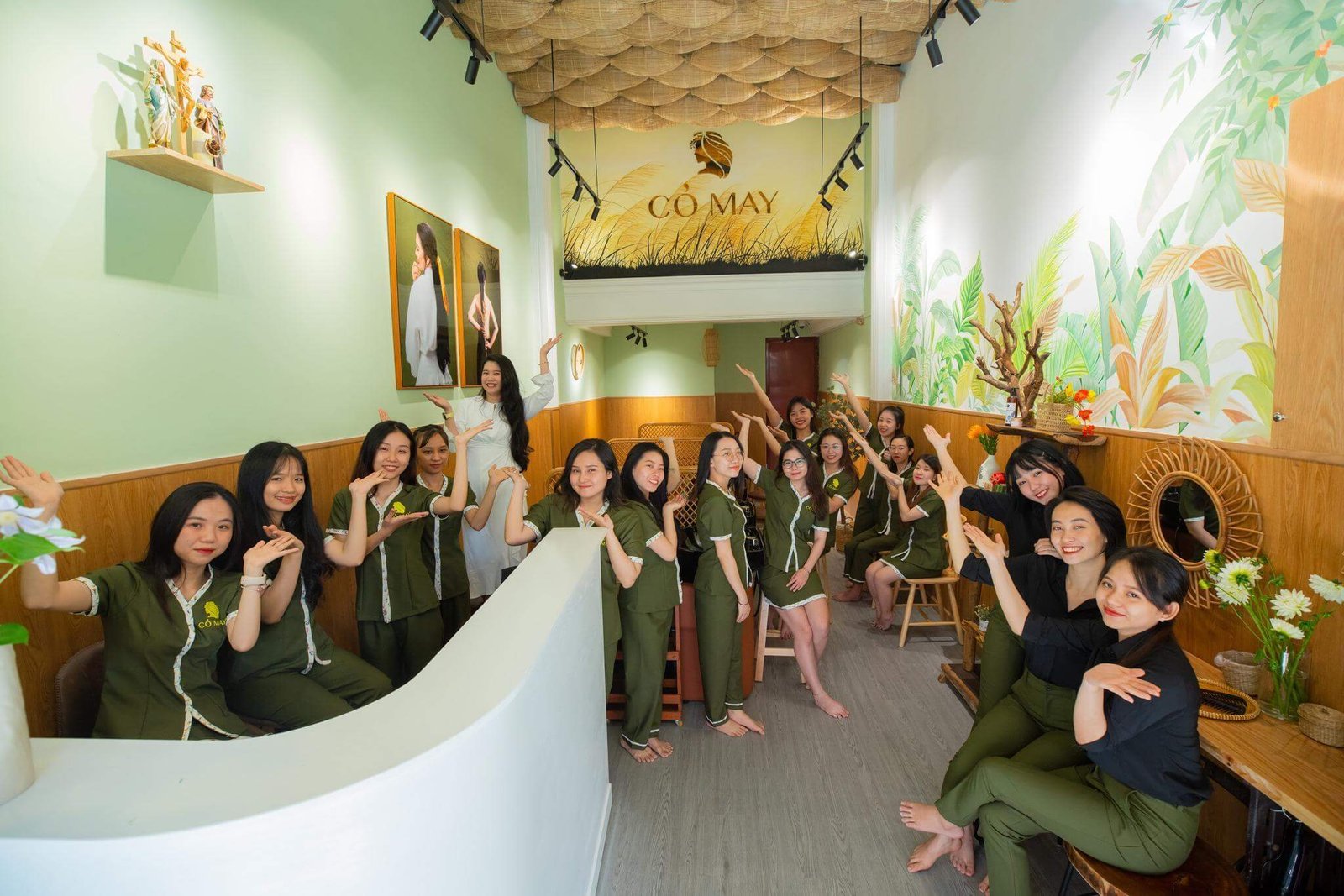 Nhân viên tiệm spa Cỏ May tạo dáng vui tươi trong không gian xanh thiên nhiên của tiệm.