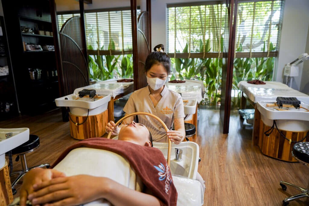 Nhân viên spa chăm sóc khách hàng trong không gian sang trọng và thư giãn, ánh sáng tự nhiên từ cửa sổ.