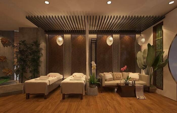 Phòng spa sang trọng, ấm cúng với giường massage đôi, ghế sofa, cây xanh và ánh sáng dịu nhẹ.