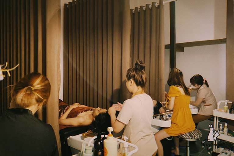 Nhân viên spa thực hiện liệu trình chăm sóc da cho khách hàng trong không gian thư giãn và ấm áp.