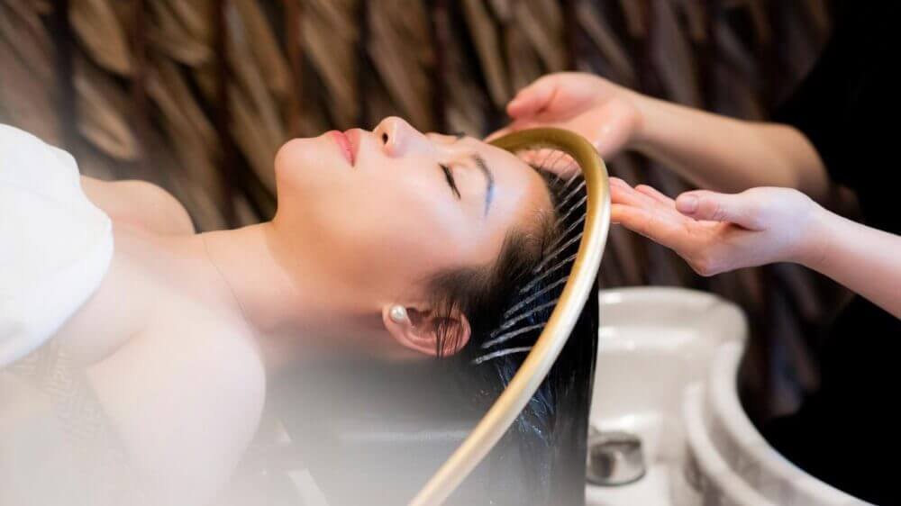 Người phụ nữ thư giãn khi gội đầu spa, dịch vụ chăm sóc tóc chuyên nghiệp và thư giãn tối đa.