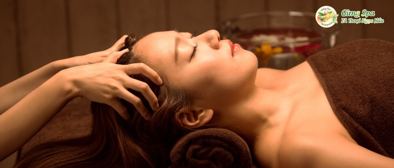 Người phụ nữ thư giãn trong liệu pháp massage đầu tại spa, không gian ấm áp và yên tĩnh.