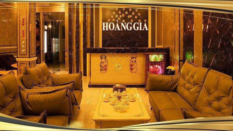 Phòng khách sạn sang trọng có ghế sofa và bàn trà với tên Hoàng Gia trên tường.