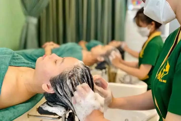 Người phụ nữ được gội đầu thư giãn trong tiệm salon spa, liệu pháp chăm sóc tóc chuyên nghiệp.