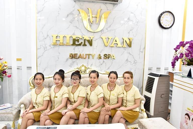 Nhân viên Hien Van Beauty & Spa ngồi trên ghế, trong không gian spa sang trọng với logo nổi bật trên nền đá.