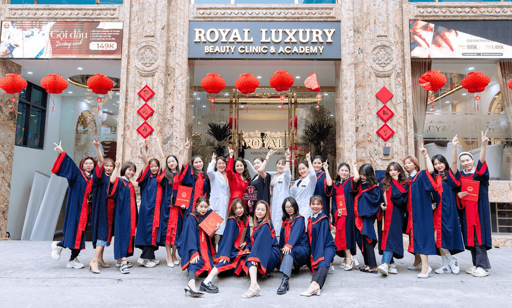 Nhóm sinh viên tốt nghiệp mặc áo cử nhân đứng trước Royal Luxury Beauty Clinic & Academy.
