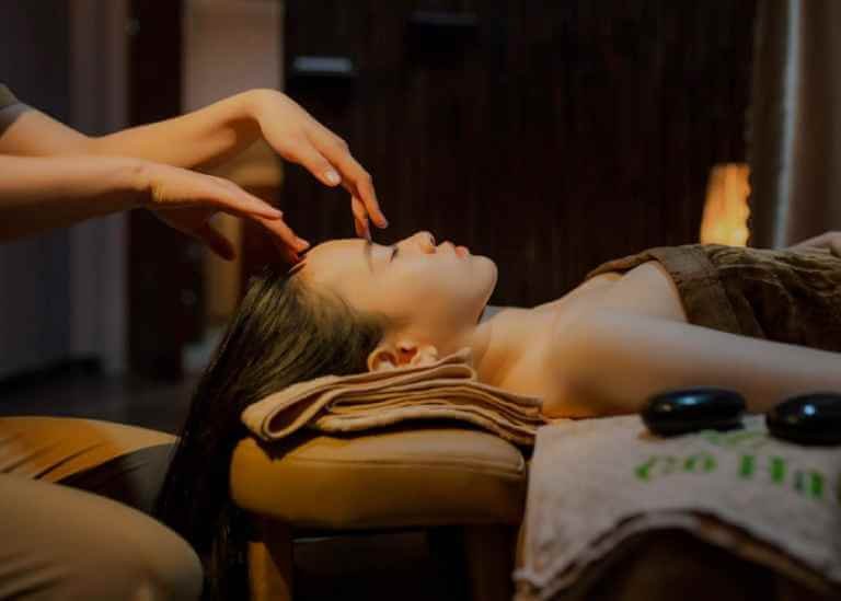 Người phụ nữ thư giãn với liệu pháp massage đầu trong không gian spa ấm cúng.