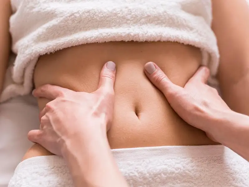 Người đang xoa bóp vùng bụng giúp thư giãn cơ và cải thiện tiêu hóa, mang lại cảm giác thoải mái và nhẹ nhõm.