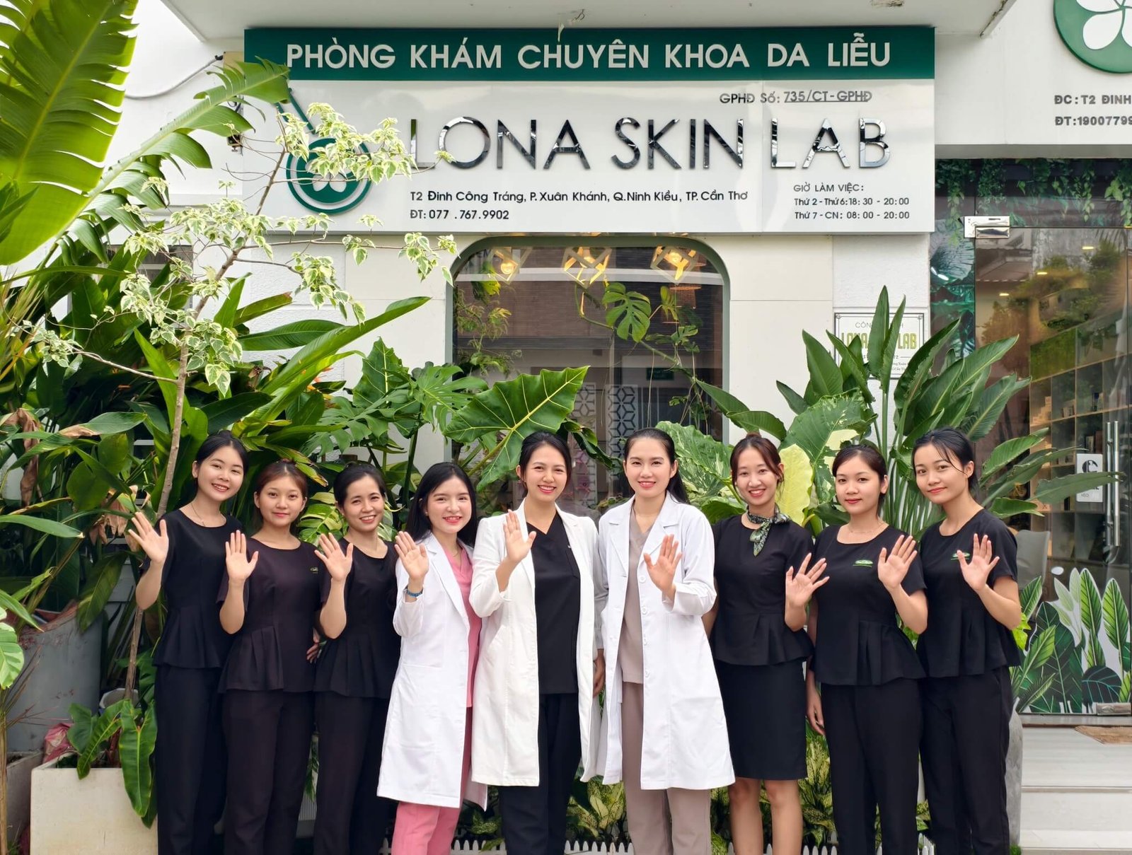 Nhóm nhân viên phòng khám da liễu Lona Skin Lab Cần Thơ tươi cười chào đón trước cửa tiệm đầy cây xanh.