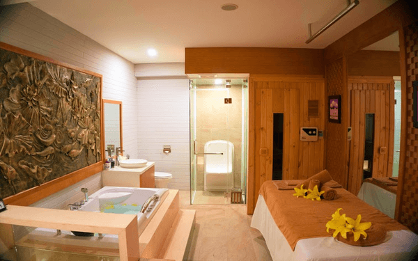 Phòng spa sang trọng với bồn tắm massage, giường thư giãn, hoa trang trí, tạo cảm giác thoải mái và thư thái.