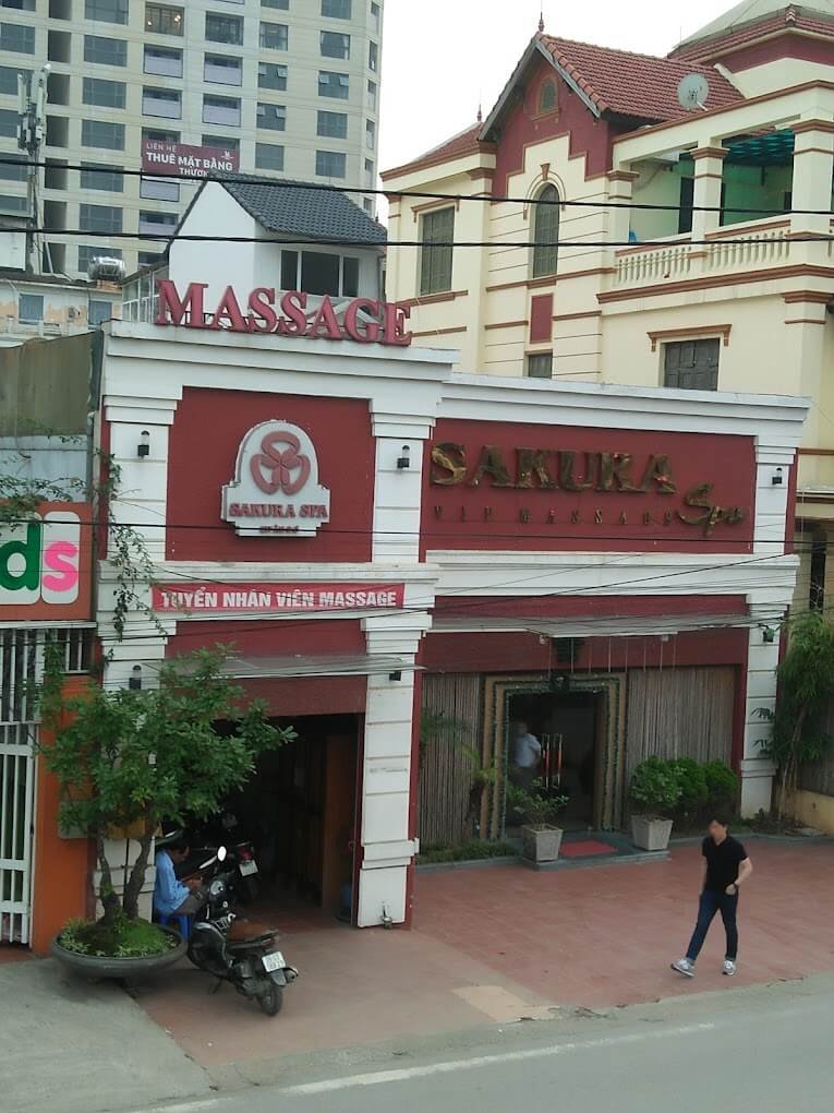Mặt tiền Sakura Spa với biển hiệu tuyển nhân viên massage, nằm trong khu vực đô thị sầm uất.