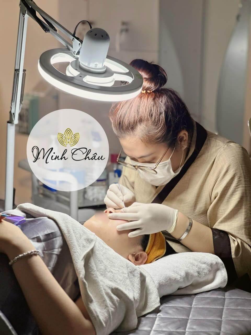 Kỹ thuật viên Minh Châu thực hiện chăm sóc da mặt chuyên nghiệp dưới ánh đèn chiếu sáng.
