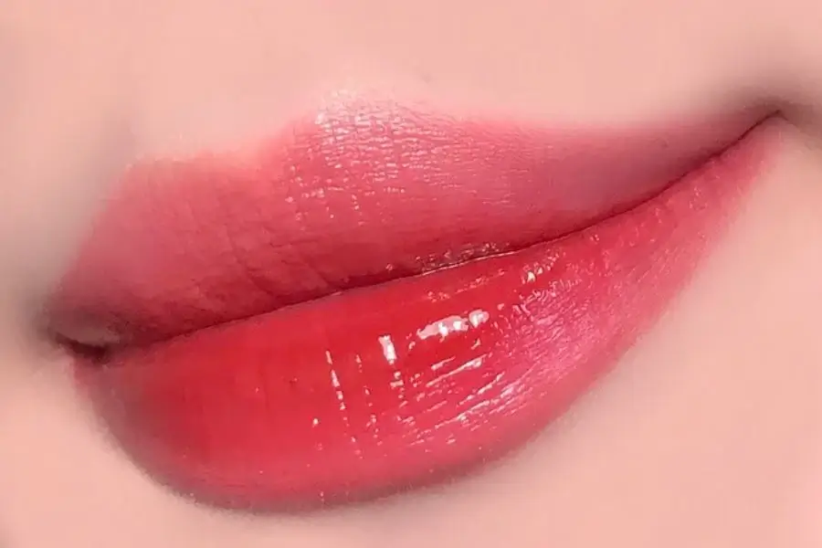 Đôi môi được tô son đỏ tươi sáng bóng, tạo vẻ căng mọng và quyến rũ.