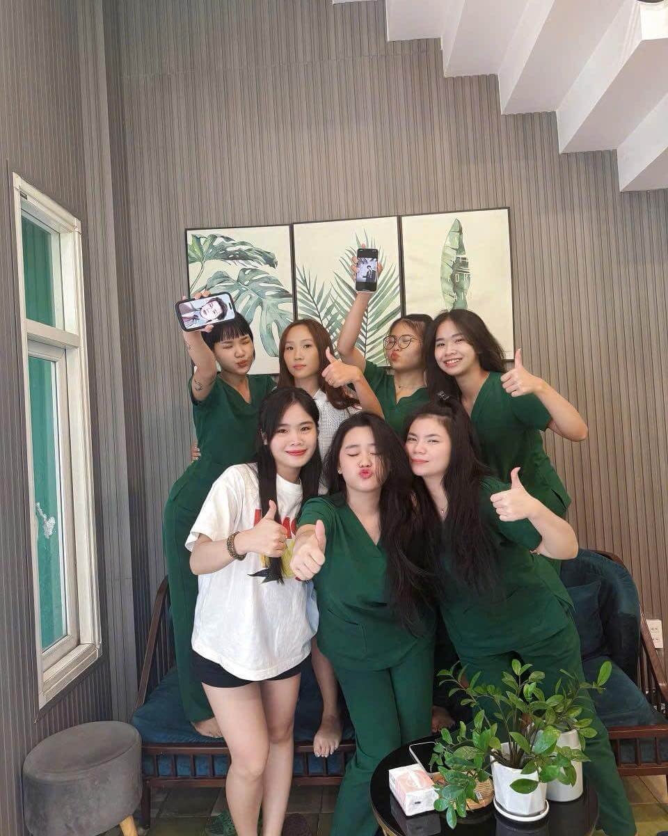 Nhóm các cô gái vui vẻ chụp ảnh trong phòng khách với cây xanh và tranh nghệ thuật trang trí.