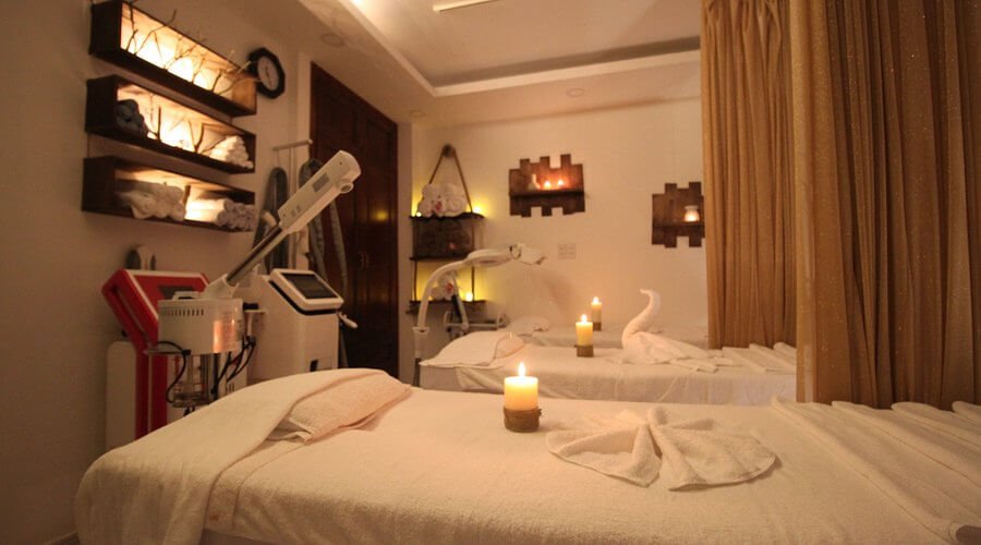 Phòng spa với giường massage, nến thơm và ánh sáng dịu nhẹ, tạo không gian thư giãn và yên tĩnh.