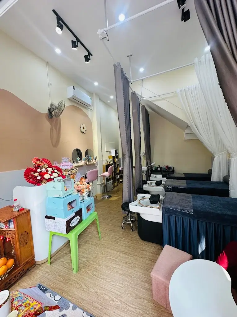 Nội thất spa sang trọng với giường massage, ghế làm nail và trang trí hoa, tạo không gian thư giãn và dễ chịu.