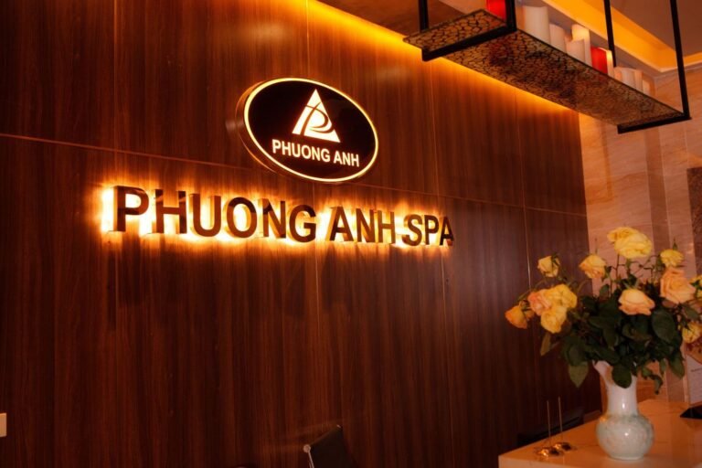 Biển hiệu Phuong Anh Spa với ánh sáng vàng ấm áp, kệ nến và bình hoa tươi sáng.