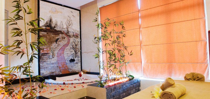 Phòng spa thư giãn với bồn tắm, cây xanh và nến tạo không khí ấm cúng.