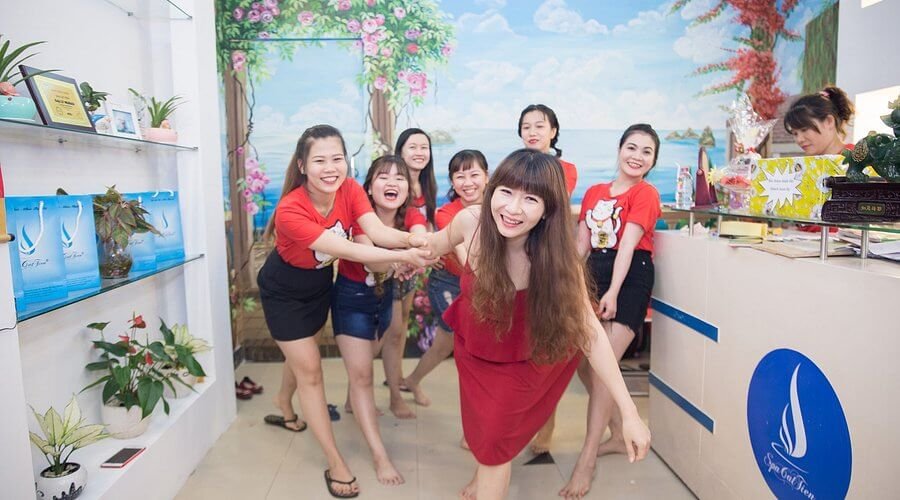 Nhóm bạn trẻ vui vẻ tạo dáng trong spa với thiết kế cây xanh và hoa, tạo không khí tươi mới và năng động.