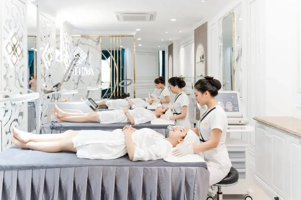 Nhân viên spa chăm sóc da mặt khách hàng trong không gian thẩm mỹ viện sang trọng.
