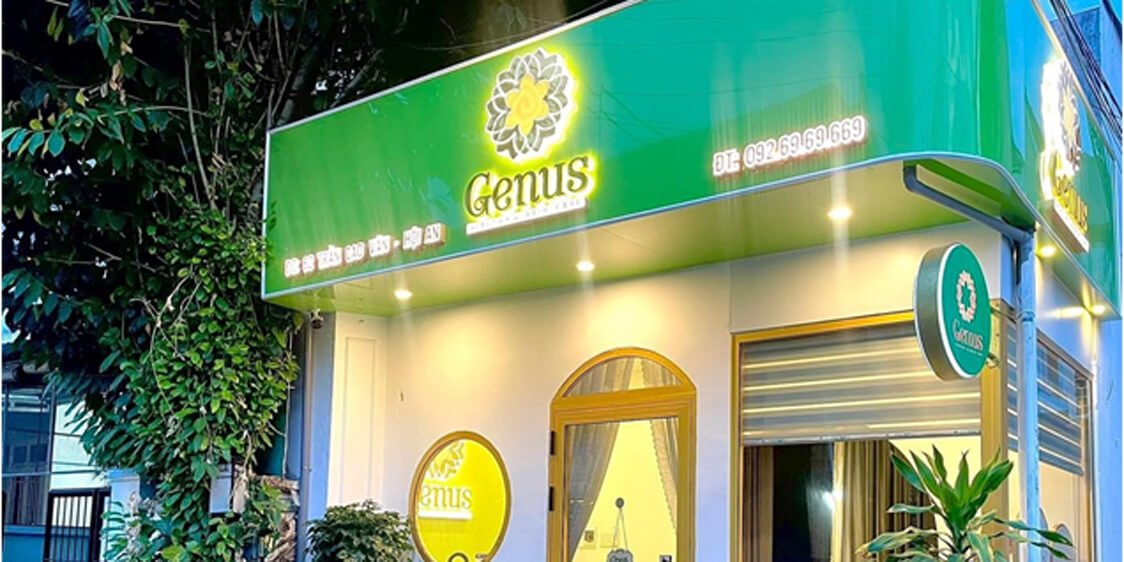 Mặt tiền cửa hàng Genus với biển hiệu xanh lá cây nổi bật và ánh đèn chiếu sáng ấm áp.