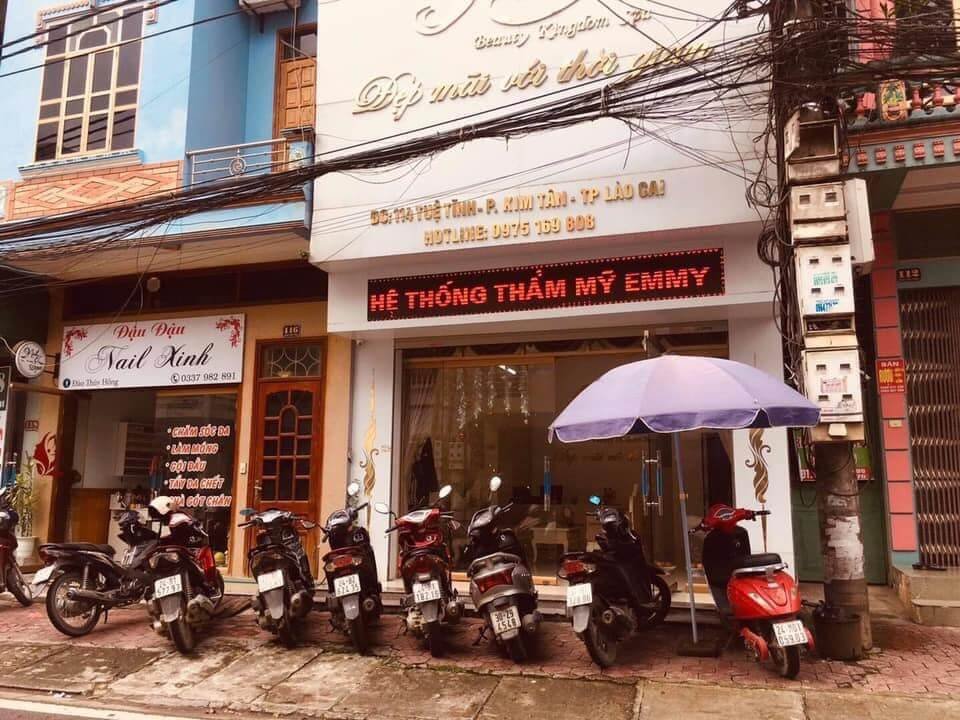 Dãy xe máy đậu trước cửa hàng thẩm mỹ Emmy và tiệm nail Xinh trên đường phố Lào Cai, Việt Nam.